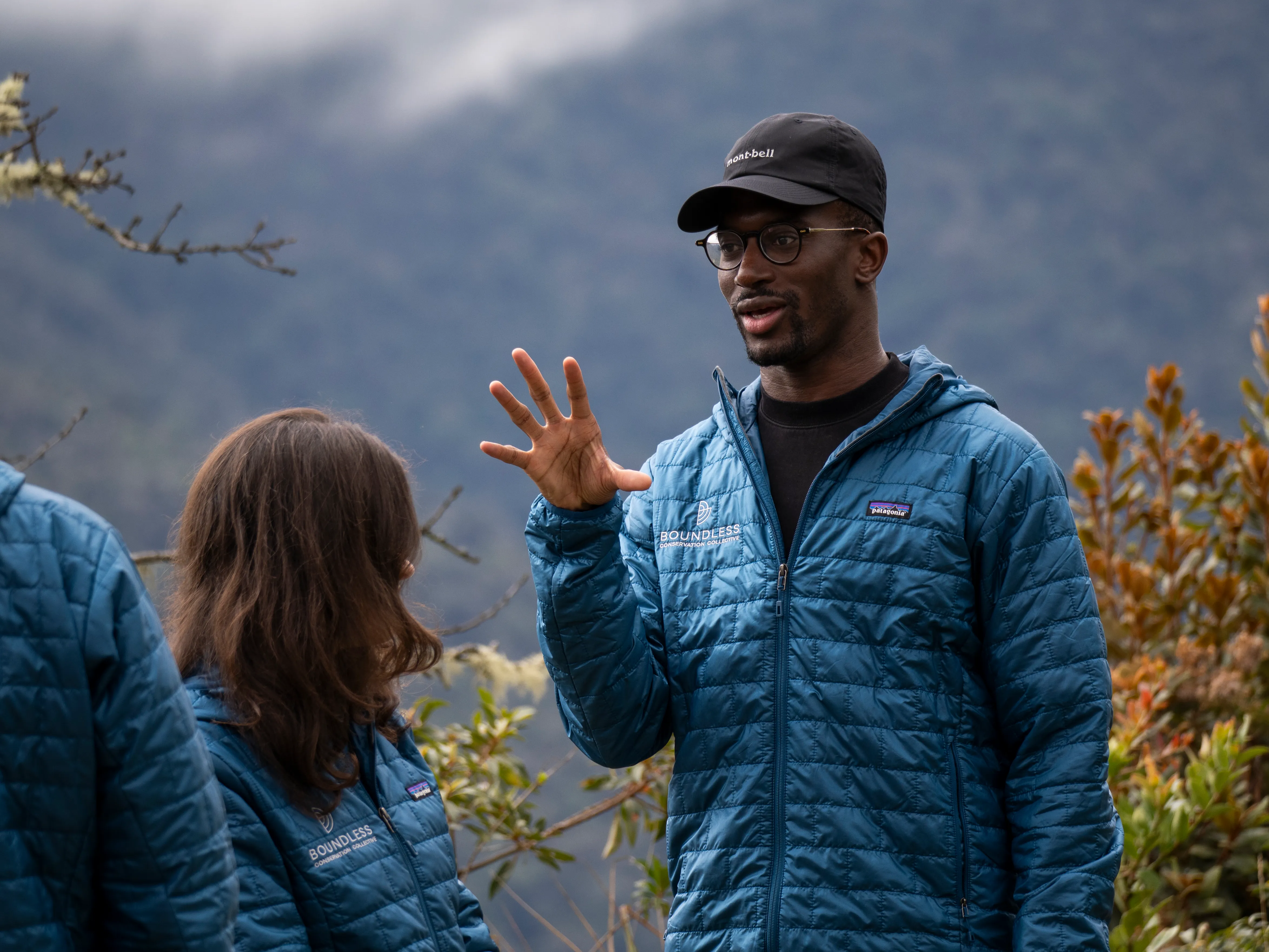 A woman sitting in a lush, green forest, writing in a notebook