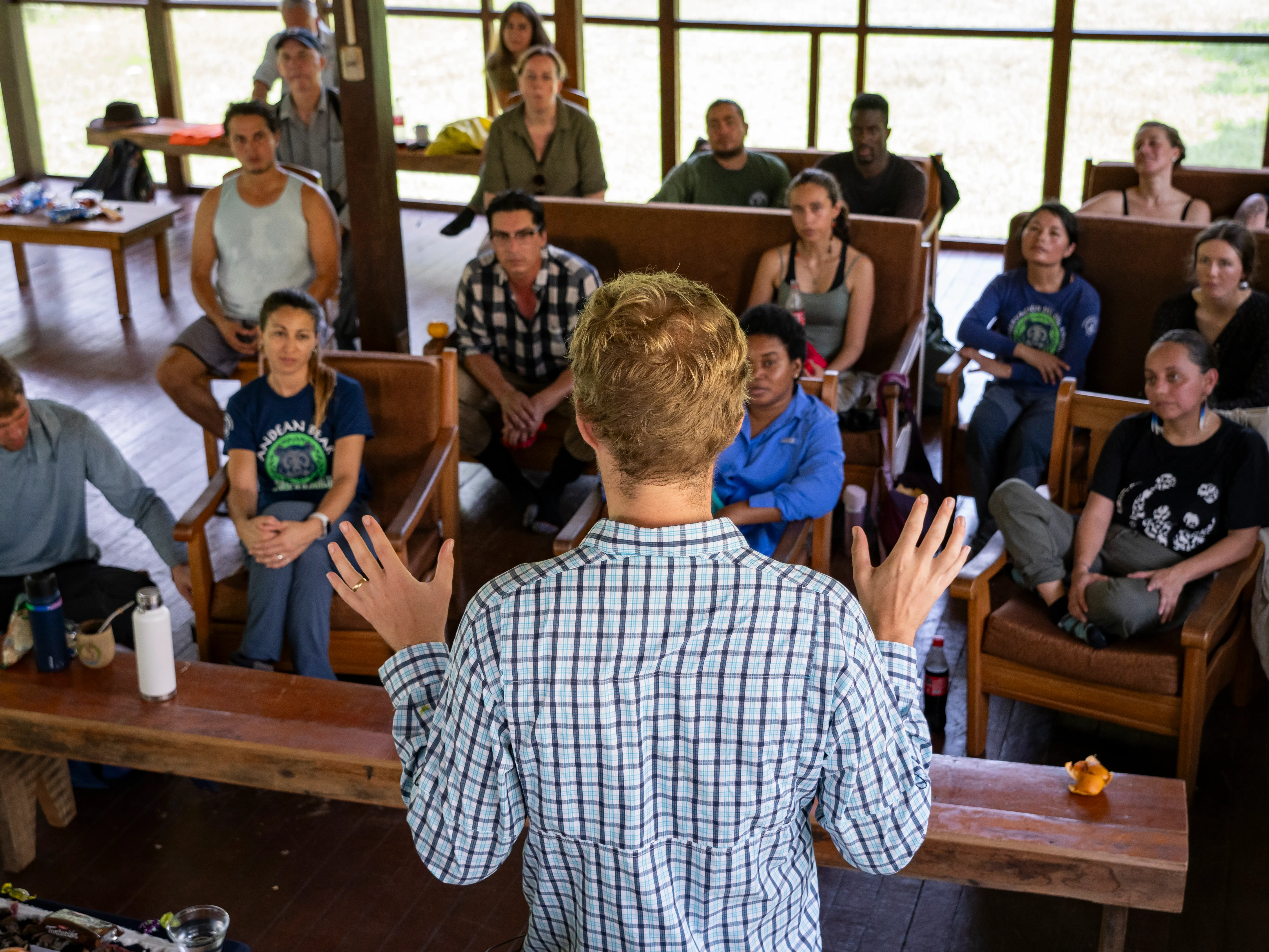 A full audience sitting in a large lecture hall, with two speakers in the foreground.