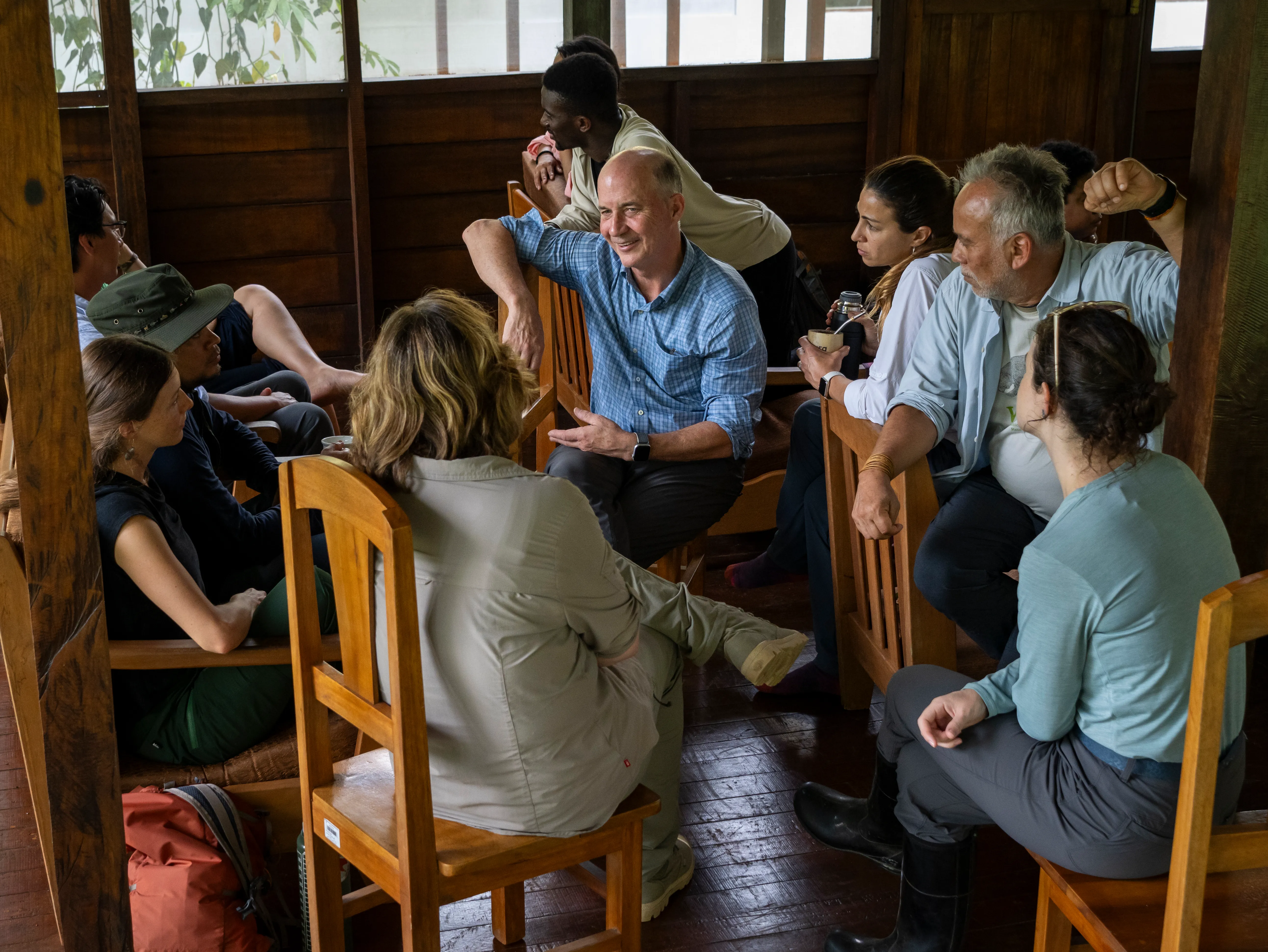 A woman in a soft plaid shirt carrying a large bundle of green reeds over her head